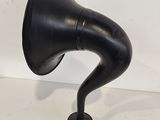 an old black gramphone on a stand with a white wall in the background
