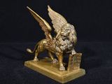 une statue en or représentant un lion ailé portant un panier sur le dos