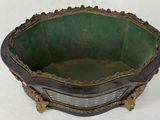 an old green and black bowl sitting on top of a white table