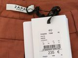 the label on the back of a brown pants is attached to a tag