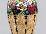 un vase avec des fleurs peintes dessus, posé sur une table