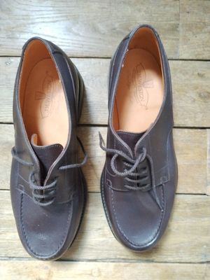 une paire de chaussures en cuir marron à lacets posée sur un parquet