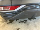 the rear end of a gray car with a sticker on it ' s bumper