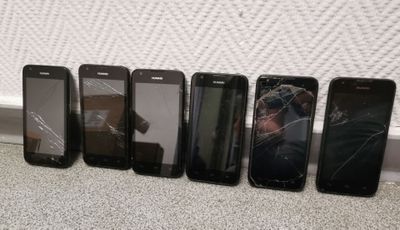 six cell phones are lined up in a row on the floor