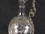 a clear glass vase with a silver handle on a black background