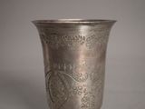 une coupe en argent ancien posée sur un socle, sur fond gris