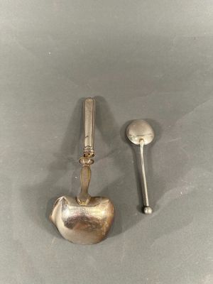 two silver spoons and a spoon rest on a table