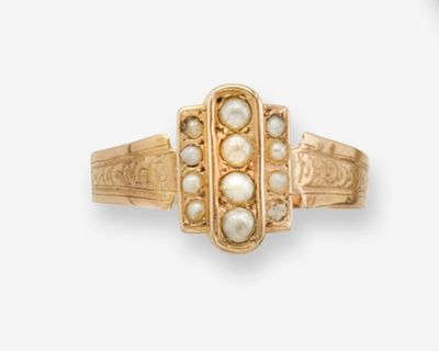 un gros plan d'une bague en or ornée de perles sur fond blanc