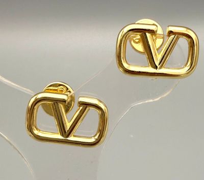 paire de boucles d'oreilles clous plaquées or en forme de « V » sur un fond transparent
