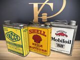 three vintage shell oil cans sitting on top of a wooden table