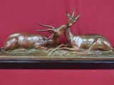 sculpture en bronze représentant deux cerfs couchés sur un socle en bois