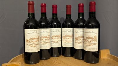 four bottles of red wine sitting on top of a wooden barrel