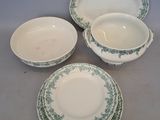 quatre pièces de vaisselle verte et blanche posées sur une table