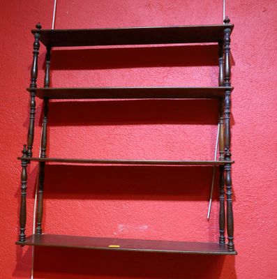 a wooden shelf with three shelves on it against a red wall