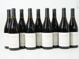 six bouteilles de vin sont alignées sur une surface blanche