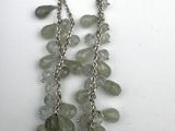 a close up of a necklace with green beads on a white surface