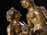 an antique bronze statue of a man and a woman with a basket of grapes