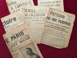 plusieurs vieux journaux français posés sur une table rouge