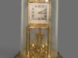 an image of a gold clock under a glass dome on a table