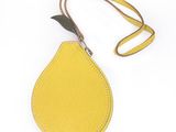 un sac à main en forme de citron muni d'une lanière en cuir, sur fond blanc