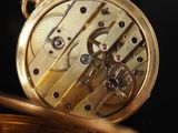 a close up of a gold pocket watch with a black background