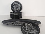 black and white plates with fish designs on them sitting on a table