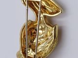 a gold brooch of a bird with a golf club in its beak