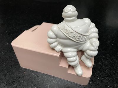 une figurine représentant un homme corpulent assis sur une boîte rose