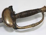 a sword with a gold handle on a white surface