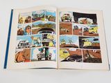 an open comic book with a picture of a man driving a car