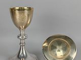 silver goblet and plate sitting on a table next to each other