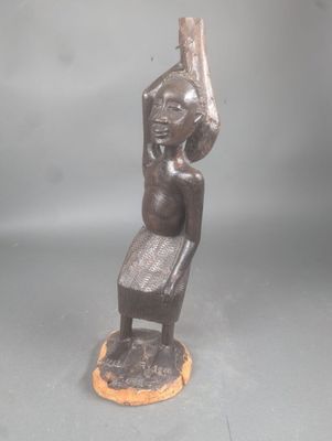 statue d'une femme assise sur une chaise, les bras levés