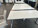 des tables et des chaises dans un bureau, sur lesquelles sont posés des écrans d'ordinateur
