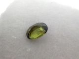 a green tourmaline gems sits on a white surface