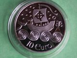 a silver coin with a ship on it on a green surface