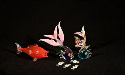 trois figurines de poissons en verre posées sur une surface noire
