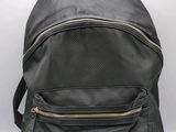 the back of a black backpack with gold zippers on it