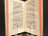 an open book sitting on top of a metal stand on top of a table