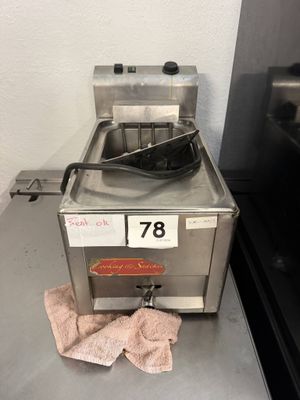 une friteuse posée sur un plan de travail, avec une serviette à côté