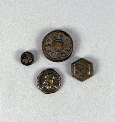 Trois types différents de boutons métalliques sont représentés sur une surface blanche