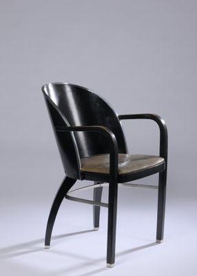 une image représentant une chaise noire avec une assise en cuir sur fond gris