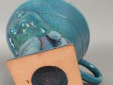 un petit vase bleu surmonté d'une boîte en bois