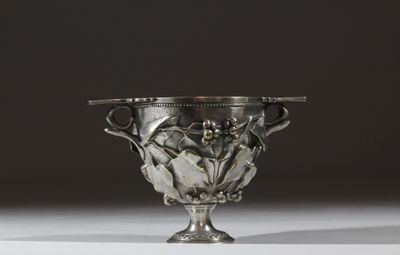 un vase ancien en argent orné de fleurs et de feuilles sur un fond blanc