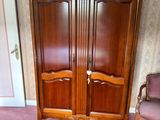 a wooden armoire in the corner of a room with a chair