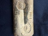 un lingot d'argent portant un poinçon, posé sur un tissu bleu