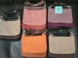 several purses are lined up on a black leather couch