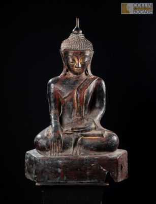 une statue représentant une personne assise sur un rocher, sur fond noir