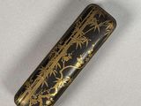 a close up of a black and gold cigarette case on a white surface