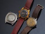 trois types de montres différents sont posés sur une surface noire