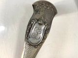 a silver spoon with a handle that has a design on it